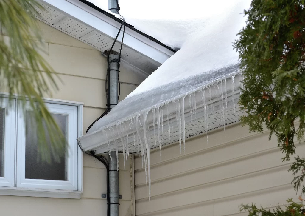 Ice dam formation on a residential roof during Minnesota winter, showing how harsh weather affects roofing materials.