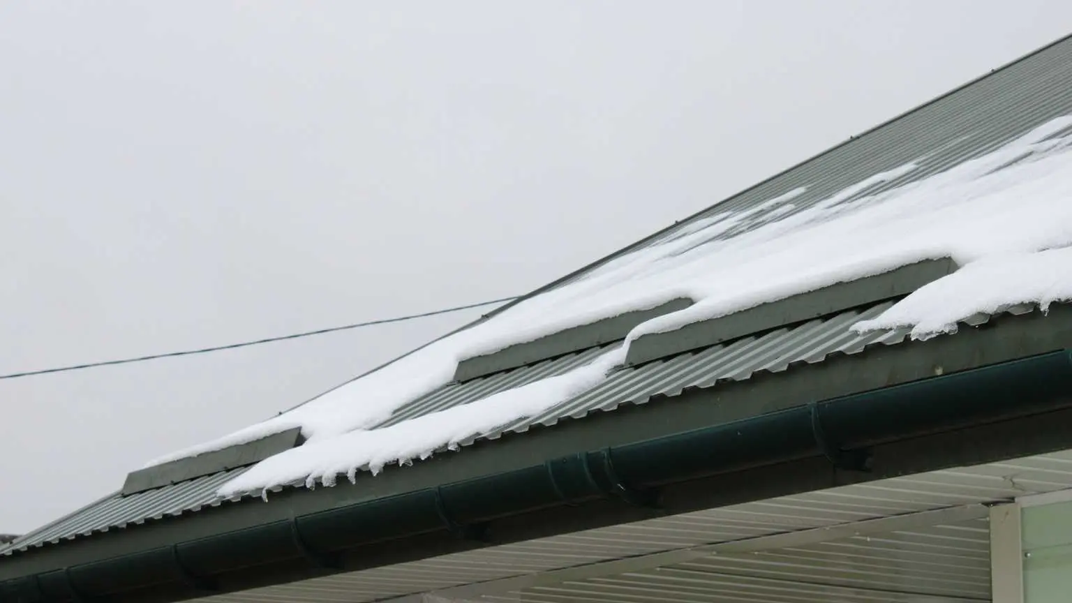 Metal roof shedding snow, showing durability in harsh winter conditions