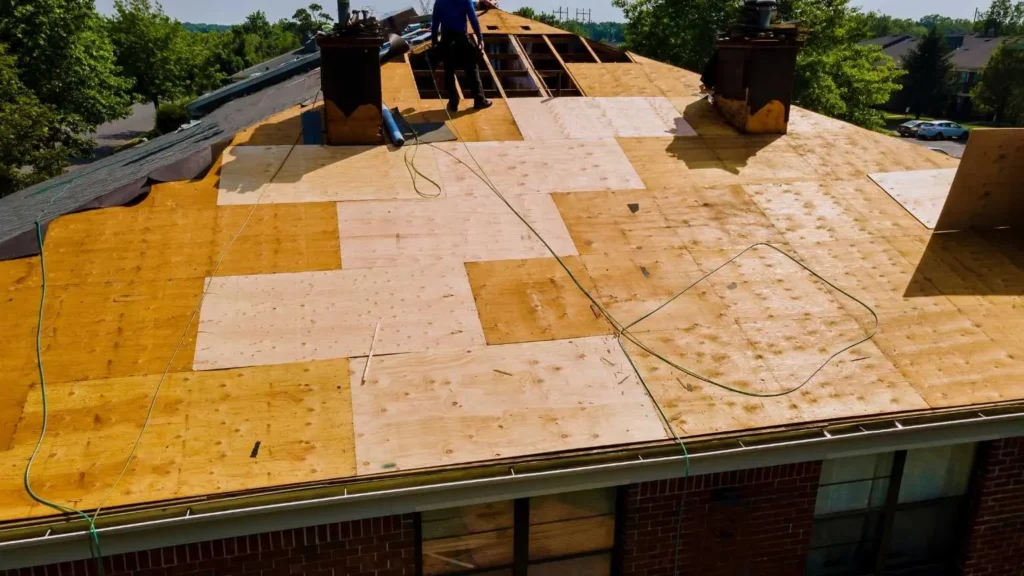 Workers installing plywood roof decking during residential roof replacement project