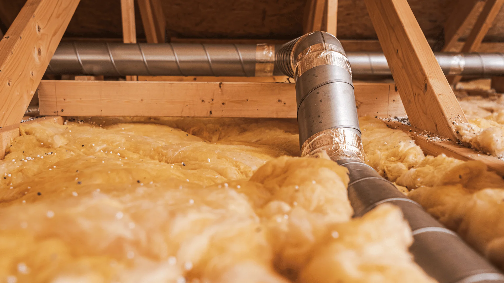 Attic insulation and ventilation ducts showing signs of poor roof ventilation in Rochester MN