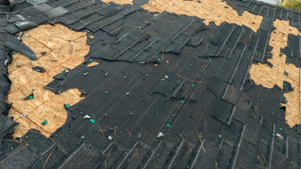 Storm-damaged roof with missing shingles and exposed decking in Rochester MN