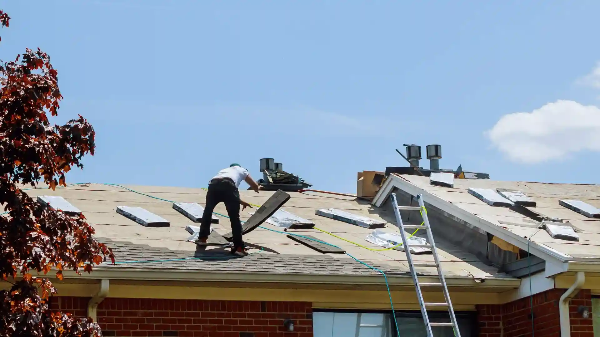 Roofer removing old shingles during full roof replacement on a residential home in Rochester MN